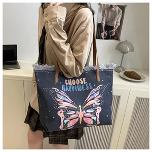 Detail of canvas tote with butterfly print, fringe edges and brown leather strap
