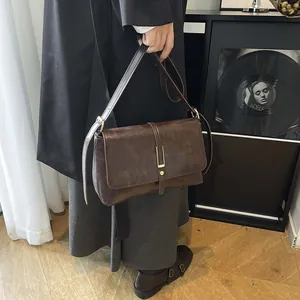 Vintage dark brown crossbody bag with gold buckle shown on shoulder for a retro look