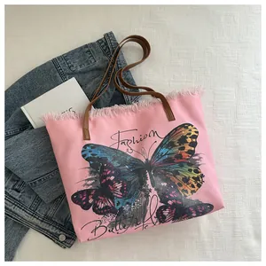 Close-up of pink canvas tote bag featuring artistic butterfly print and fringe details