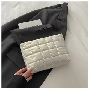 Détail d'un sac à main matelassé blanc avec motifs carrés et fermeture éclair noire