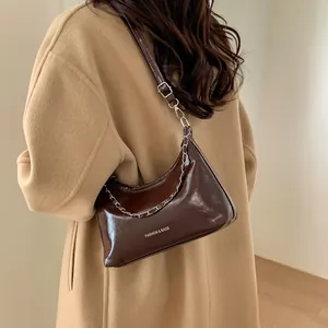 Détail du sac à bandoulière en cuir marron brillant avec chaîne argentée et sangle réglable