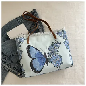 Close-up of canvas tote bag with blue butterfly print and rustic fringed edge detail