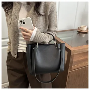 Detail of black lychee grain leather bucket bag featuring silver metal handle accents