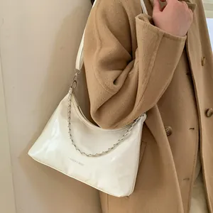 Détail d'un sac bandoulière blanc en cuir verni avec chaîne argentée et fini brillant
