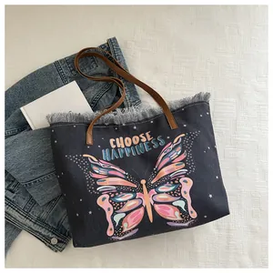 Close-up of butterfly print canvas tote bag with fringe edge and brown leather handles