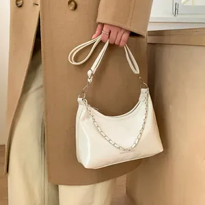 Détail du sac demi-lune blanc brillant avec chaîne argentée et bandoulière réglable