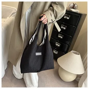 Detail of a black pleated fashion tote bag with silver label in a modern home setting