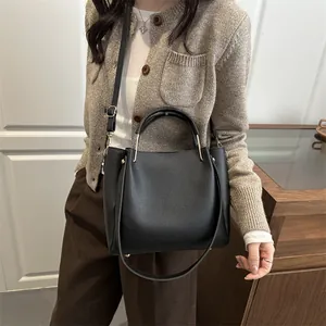 Chic black pebbled leather bucket bag with top handles and adjustable shoulder strap