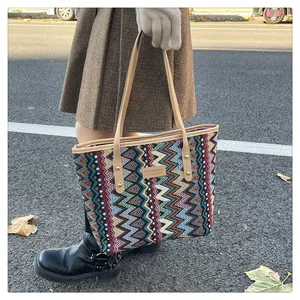 Detail einer bunten gewebten Tragetasche mit Wellenmustern und Ledergriffen im Streetstyle
