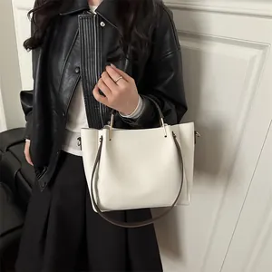 Elegant minimalist cream leather bucket bag with contrasting brown handles for daily use