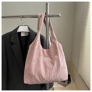 Detail of pink pleated tote bag with fashion label hanging against a black blazer