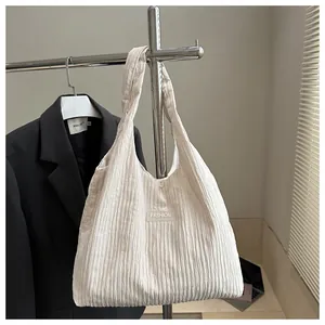 Close-up of cream-colored pleated tote bag with fashion label hanging next to a blazer