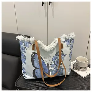 Detailaufnahme des blauen Schmetterlingsdrucks und der dichten weißen Fransen am Shopper