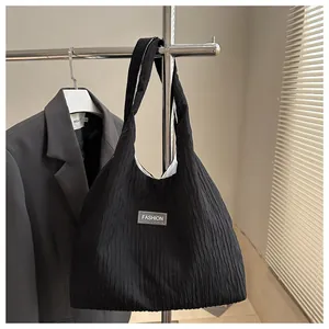 Detailed close-up of a black pleated fabric tote bag featuring a Fashion label patch
