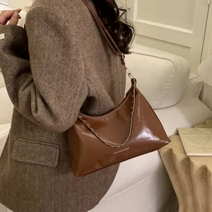 Sac à bandoulière rétro marron avec chaîne métallique et lanière en cuir sur modèle