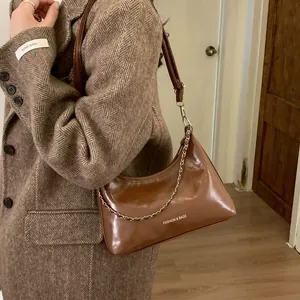 Sac demi-lune marron avec chaîne dorée porté sur un manteau d'hiver élégant