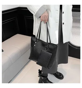 Detail of woven black tote bag featuring silver studs and matching accessory pouch