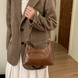 Détail d'un sac hobo marron en cuir avec chaîne argentée porté par un mannequin