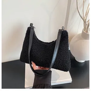 Detail shot of the black sherpa fleece texture and faux leather strap on a hobo bag