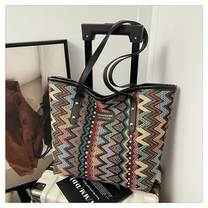 Detailansicht der gewebten Ethno-Tasche mit Zickzack-Muster auf einem weißen Koffer