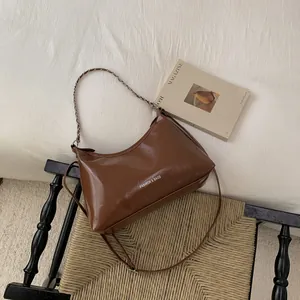 Détail du sac en cuir marron vintage avec bandoulière chaîne sur un lit blanc élégant