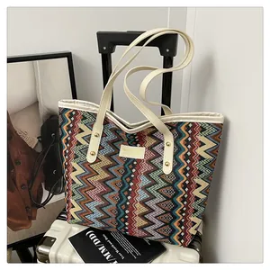 Detail einer gewebten Boho-Tasche mit Chevron-Muster auf einem weißen Koffer