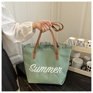 Détail du cabas en toile vert avocat avec broderie Summer et bords effilochés