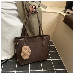 Detail der kaffeebraunen Wildleder-Tote-Bag mit Plüschwelpen-Anhänger und langem Riemen