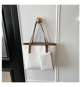 Close-up of white woven tote bag with brown handles and a matching mini coin purse detail