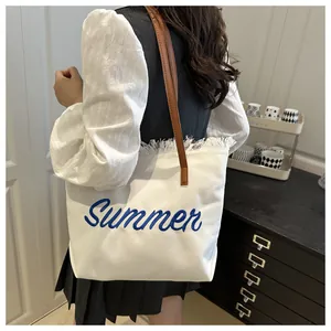 Détail du cabas en toile avec broderie Summer, bords effilochés et poignées en cuir brun