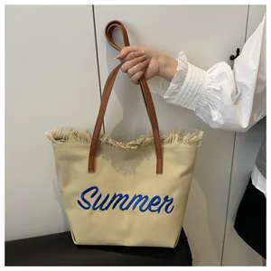 Détail du cabas en toile avec bords effilochés et broderie bleue Summer