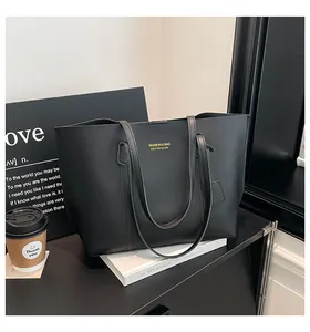 Detail of a black faux leather tote bag with gold lettering placed on books