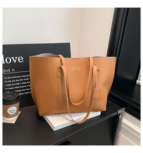 Detail of camel leather tote bag with gold logo placed on minimalist furniture