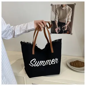 Gros plan sur le fourre-tout en toile noire avec broderie Summer et bord à franges