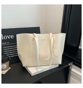 Detail of off-white leather tote bag featuring elegant lettering and a matching luggage tag