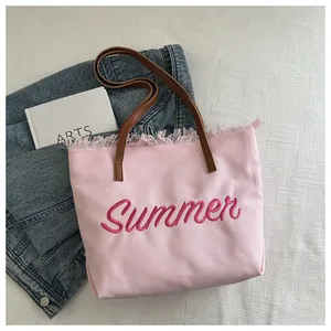 Détail du cabas en toile rose clair avec broderie Summer et bords à franges tendance