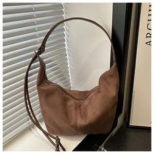 Close-up of brown suede hobo bag with adjustable strap and vertical stitching details