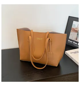 Close-up of brown leather tote bag on wooden table with gold brand lettering detail
