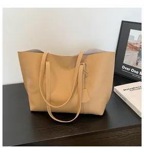 Close-up of khaki leather tote bag with gold logo on a dark minimalist wooden table