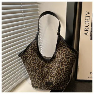 Gros plan du sac fourre-tout léopard avec finitions en cuir noir et anneaux dorés