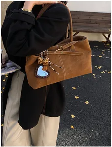 Close-up of brown suede tote bag with contrast stitching and heart leopard mirror charm