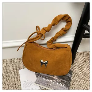 Detail of hobo bag in tan suede with ruched shoulder strap and silver butterfly buckle