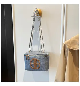 Détail du sac bandoulière en feutre gris-bleu avec logo doré et double fermeture