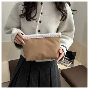 Dettaglio di una pochette in pelle testurizzata marrone con bordo in finta pelliccia bianca