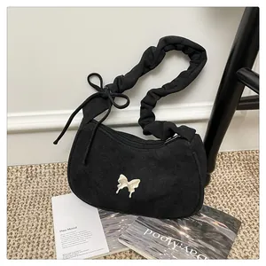 Detailed shot of black crescent shoulder bag with silver butterfly and pleated strap