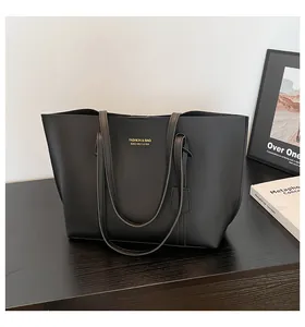 Detailed view of large black matte tote bag with gold logo on dark wooden surface