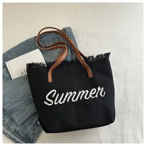 Détail du sac cabas en toile noire avec broderie Summer blanche et bords effilochés