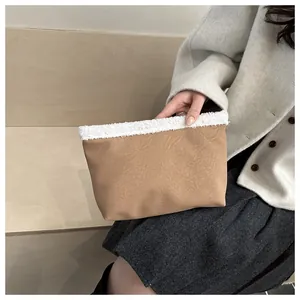 Dettaglio pochette testurizzata marrone con bordo in pile bianco tenuta da una modella