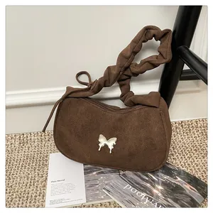 Close-up of vintage brown suede baguette bag with metal butterfly and scrunchie strap