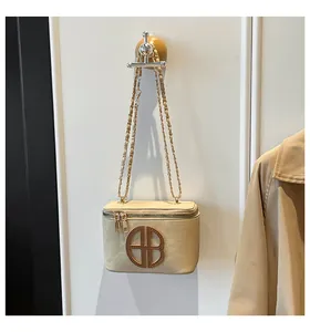 Détail du sac en daim beige avec logo doré et bandoulière en chaîne métallique